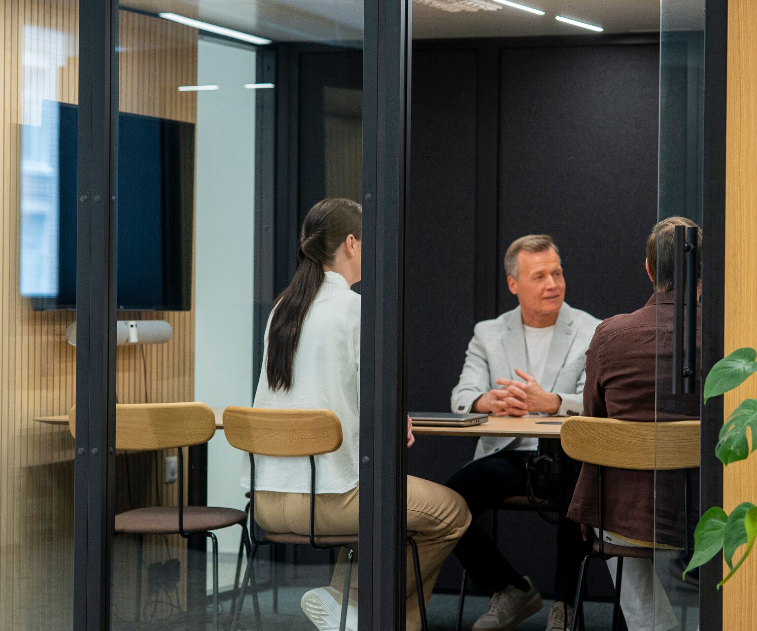 Three people sit at a desk in an Octacell workroom with an open glass door