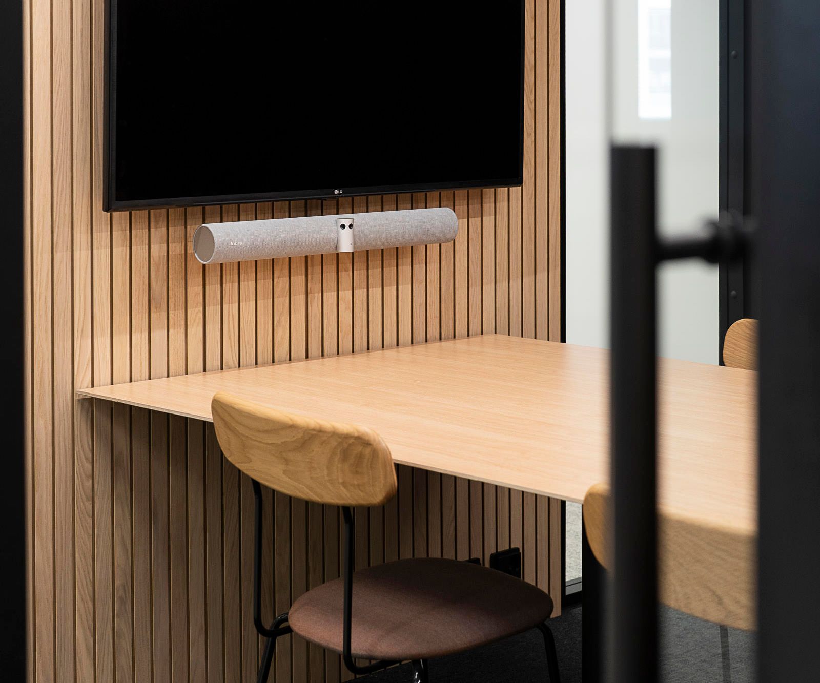 A TV monitor and speaker mounted on a wood panel wall in an Octacell workroom