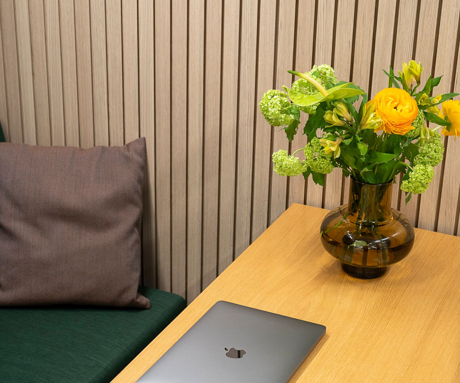 A vase with yellow-green flowers on a wooden table in an Octacell workroom