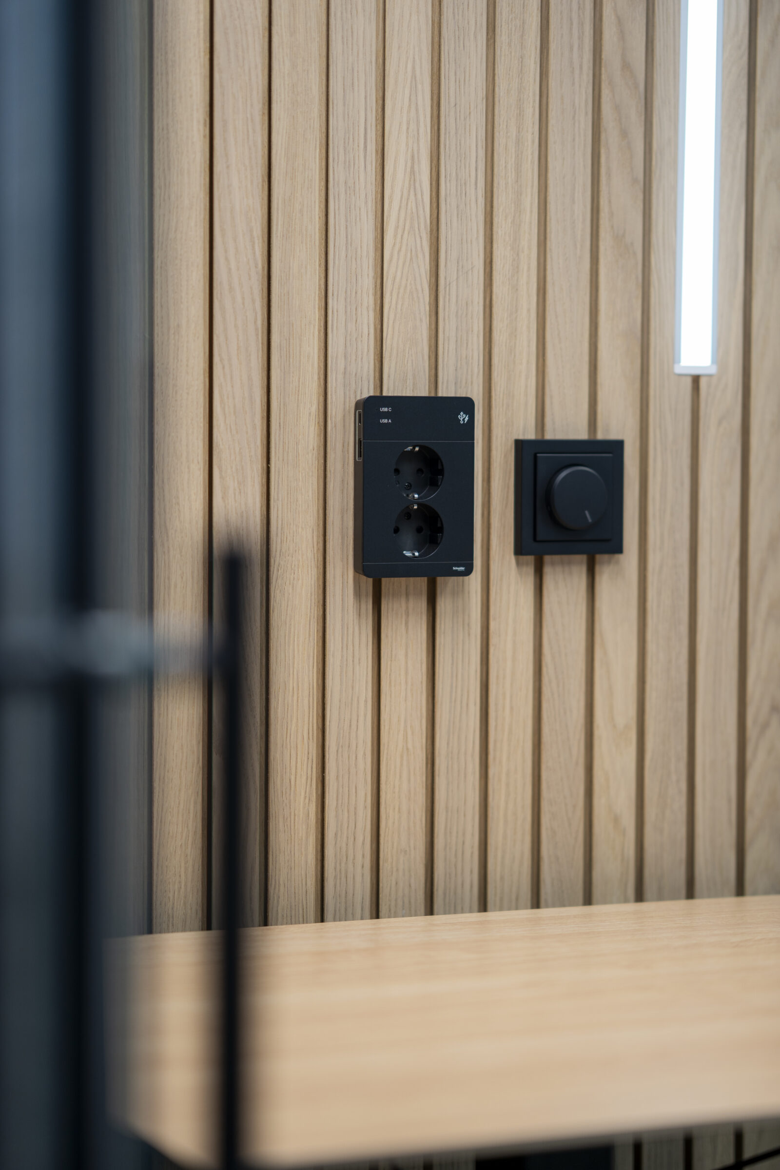 Power outlet and control dial mounted on a wooden wall inside an Octacell Workroom.
