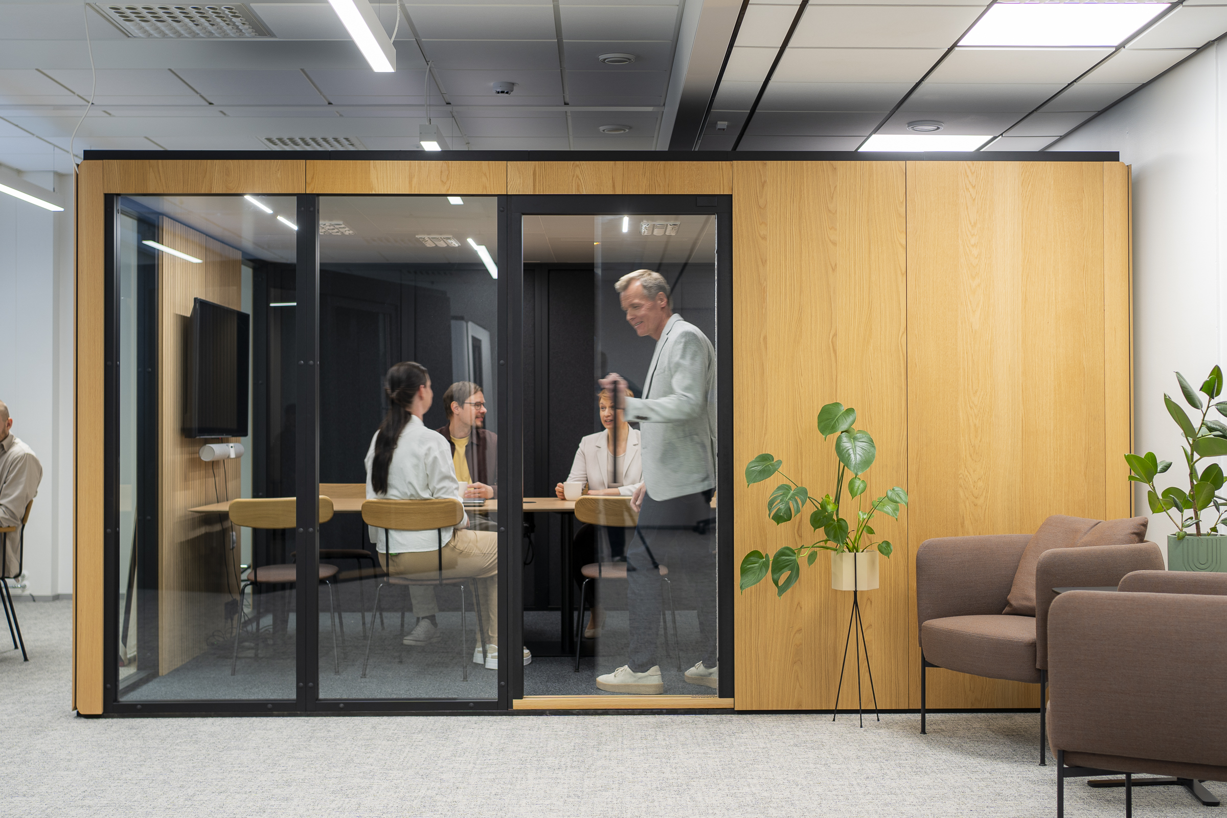 People having a meeting inside a Octacell Workroom with wooden panels.