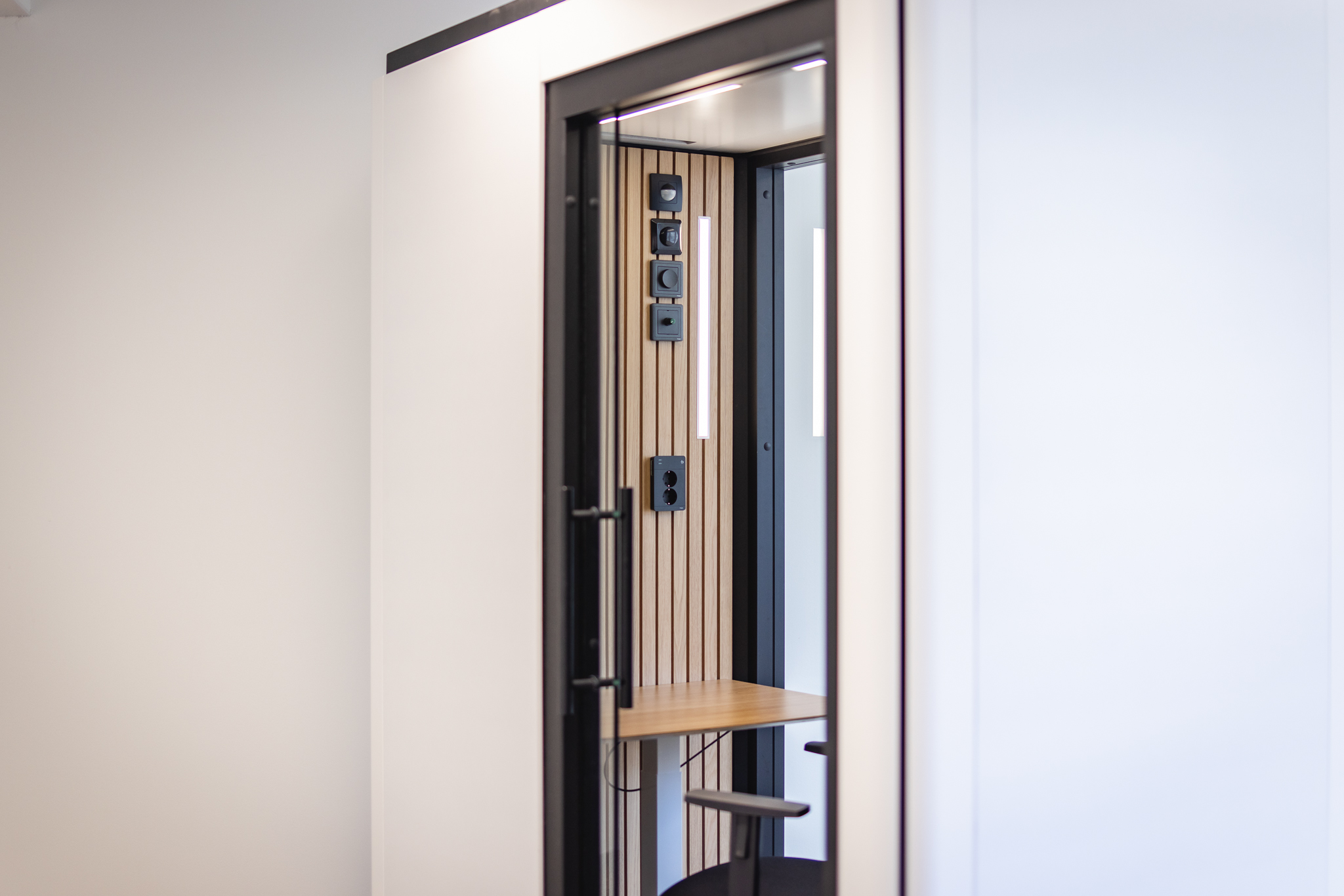 Närbild av Octacell 2X1 telefonbås inifrån med väggpaneler och knappar.