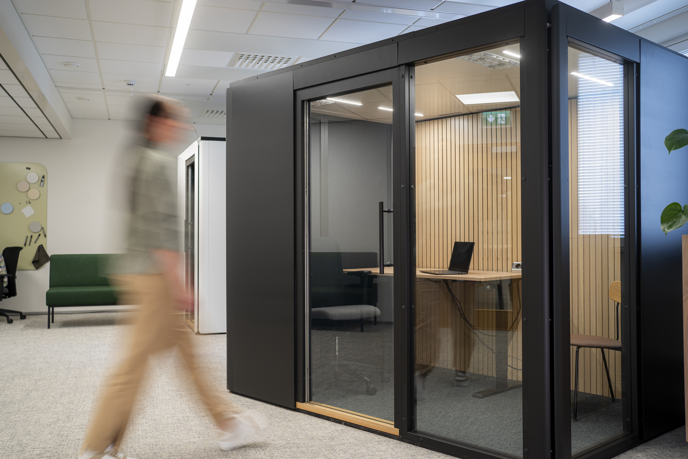 henkilö kävelemässä sisään äänieristettyn työtilaan toimistolla