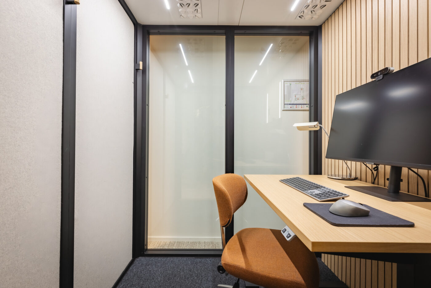 Interior of an Octacell 2X2 workroom with a desk, monitor and upholstered chair