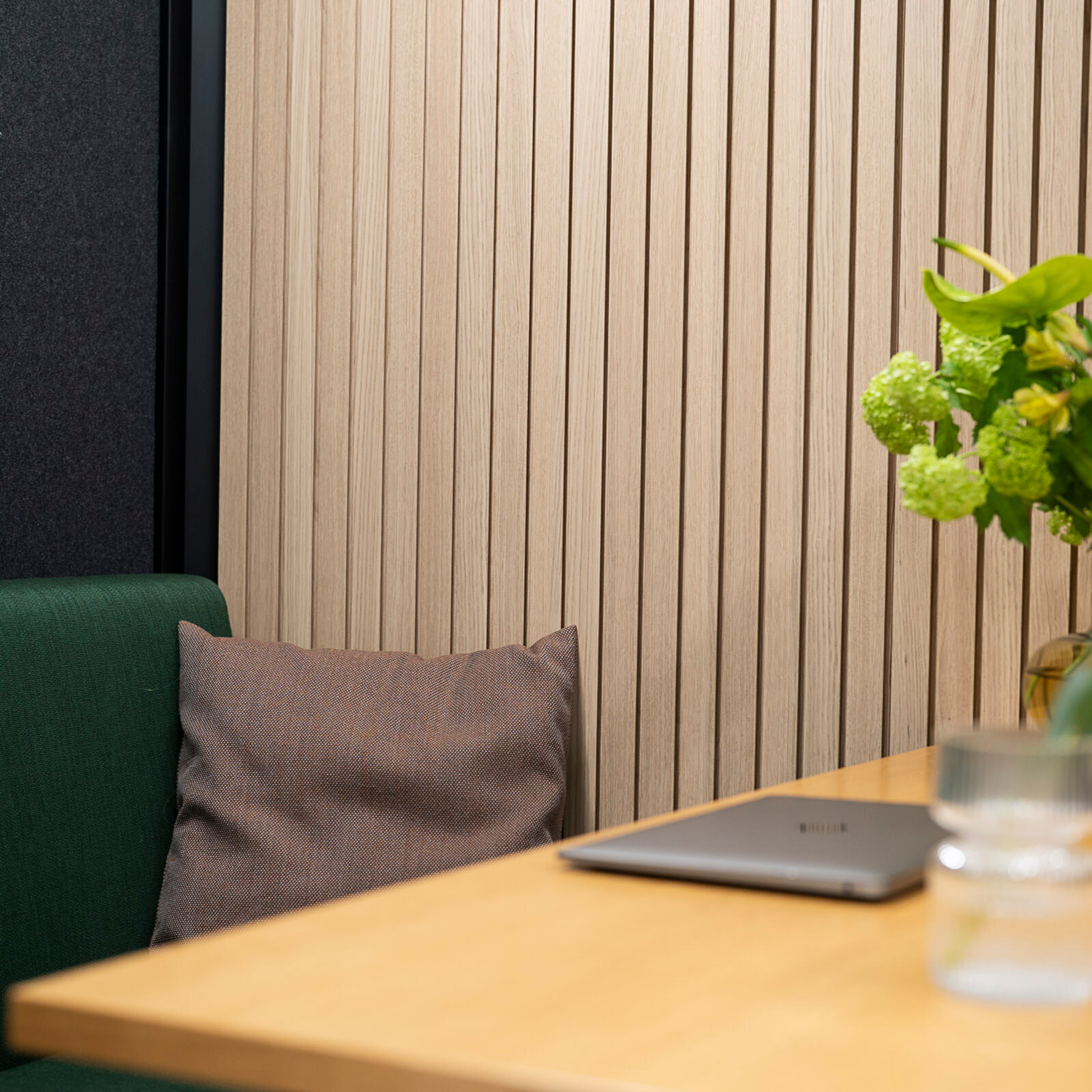 A brown pillow on a green bench behind a wood table in an Octacell workroom