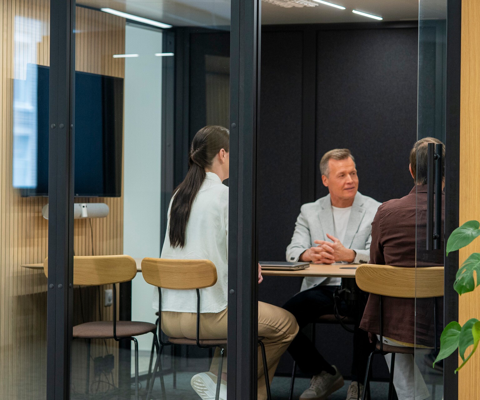 Three people sit at a desk in an Octacell workroom with an open glass door