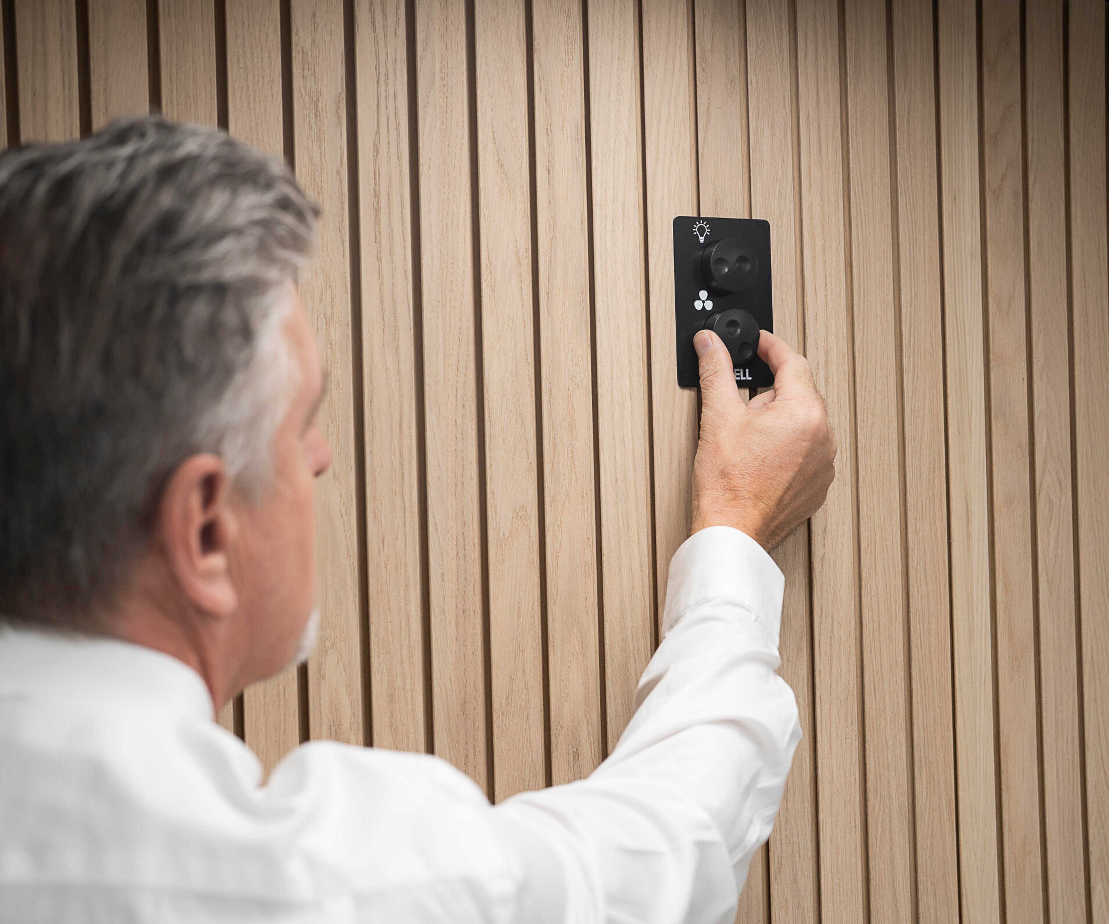 A man adjusts a dimmer switch mounted on the wall of an Octacell workroom