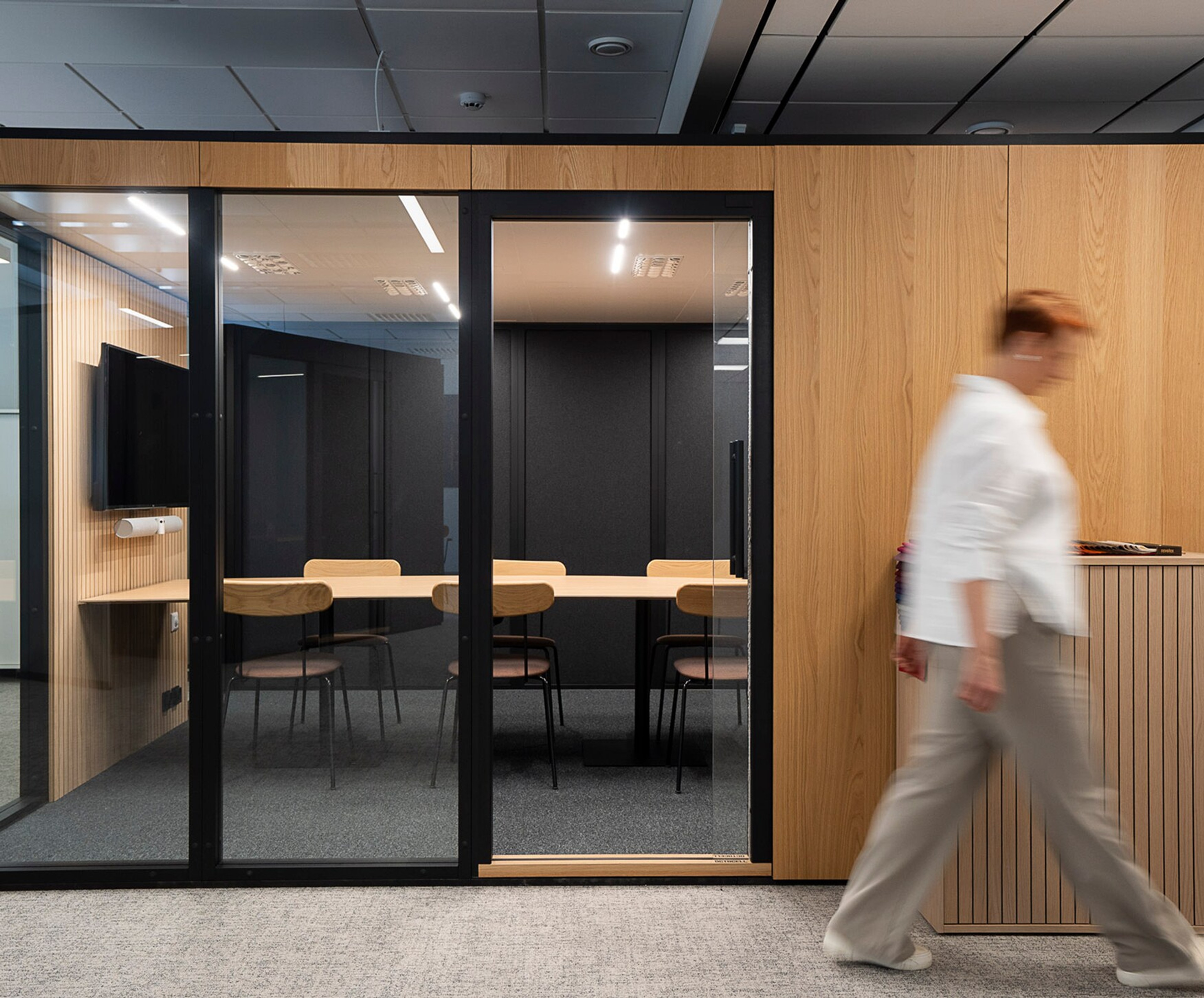 A woman walks past an Octacell workroom in an office space