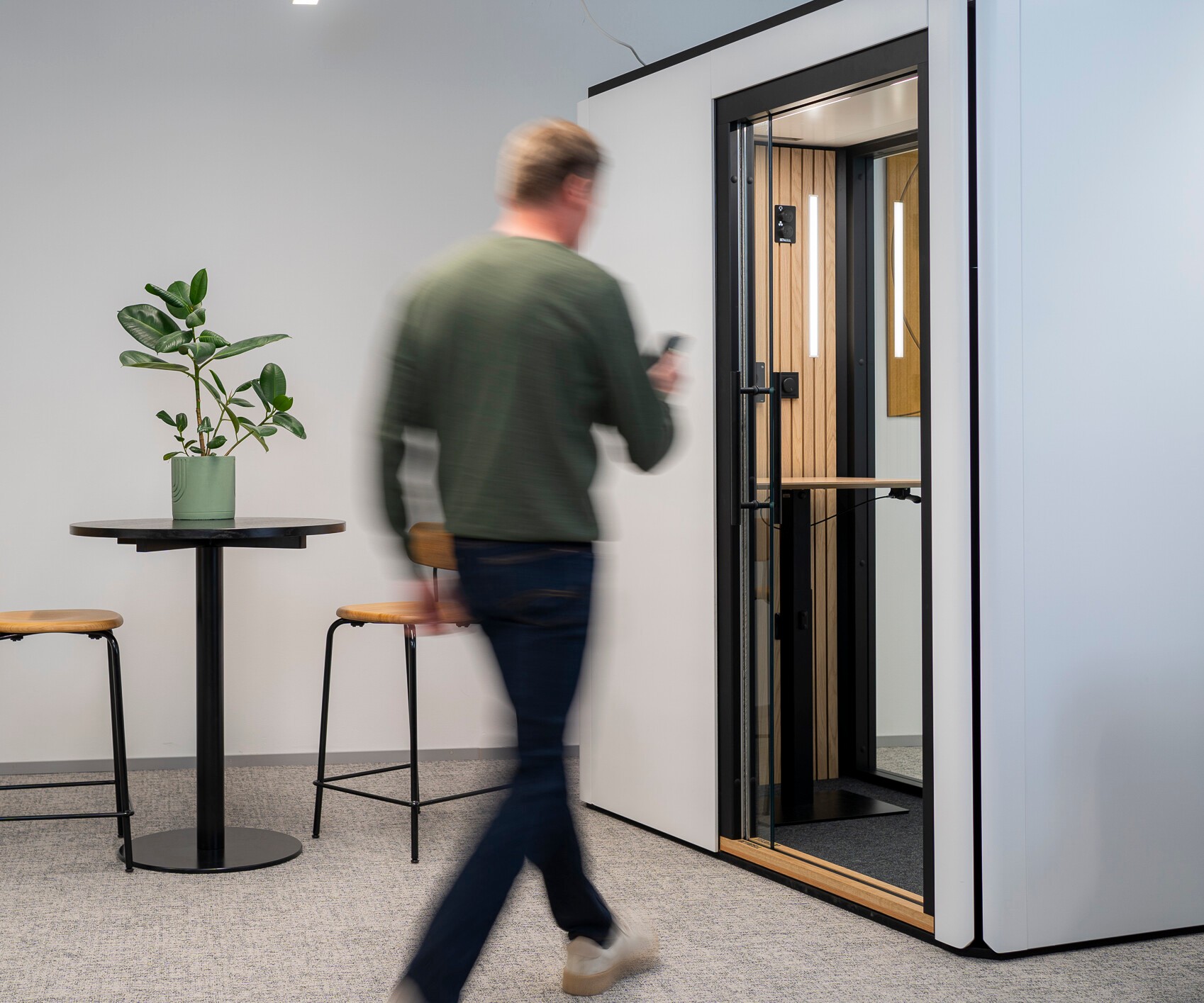 A man walks towards an Octacell call room with white surfaces