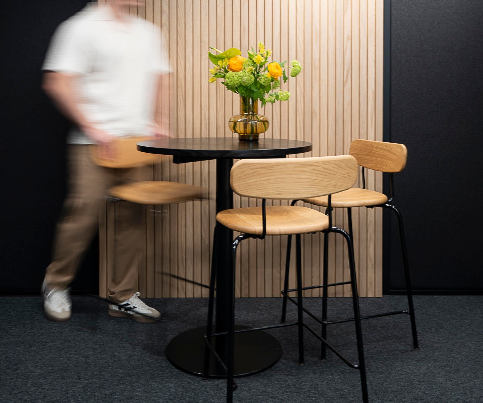 A man stands next to a round table and high chairs placed in the center of an Octacell workroom