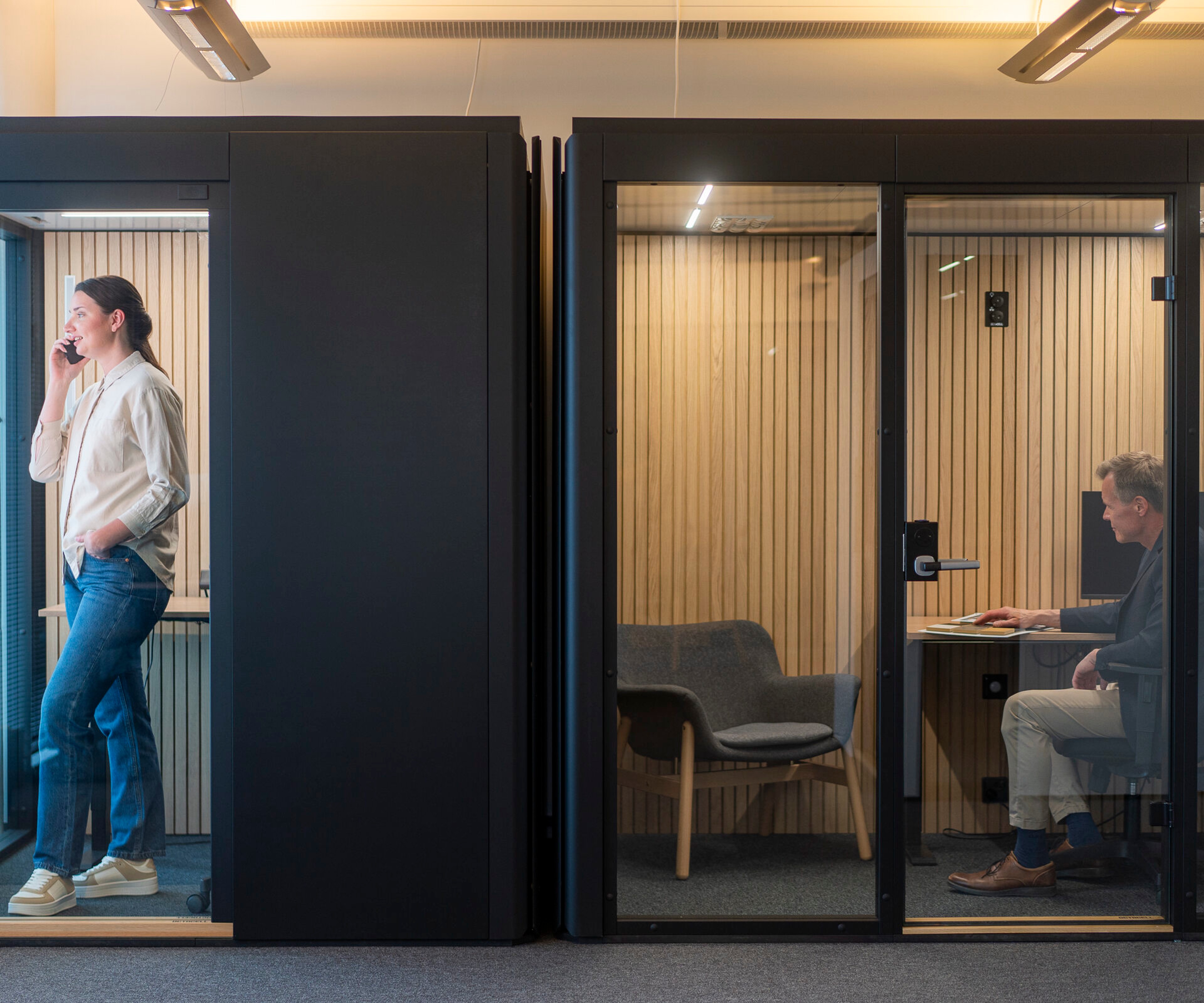 A woman stands in an Octacell call room and a man sits in an Octacell workroom